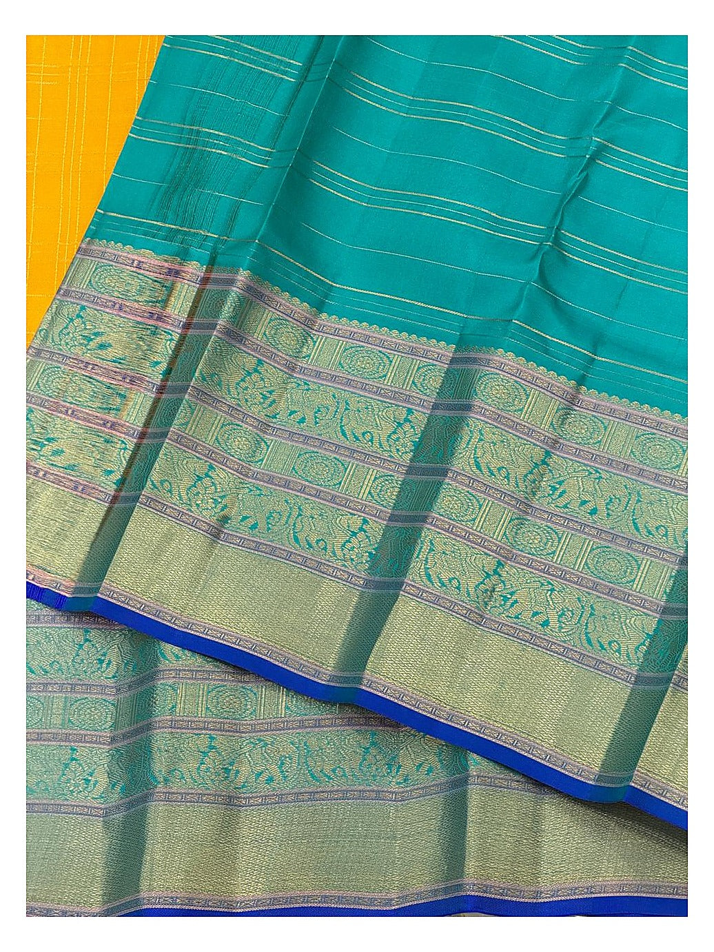 Close view of the teal pallu and broad woven motif border with mustard body contrast