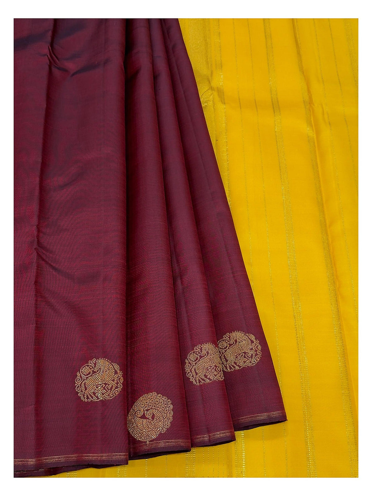 Deep wine handwoven Kanchipuram silk saree paired with bright contrast yellow section and gold-toned motifs