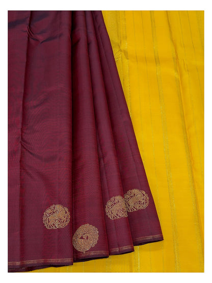 Deep wine handwoven Kanchipuram silk saree paired with bright contrast yellow section and gold-toned motifs