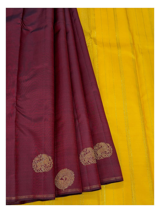 Deep wine handwoven Kanchipuram silk saree paired with bright contrast yellow section and gold-toned motifs