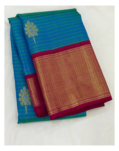 Folded teal blue Kanchipuram silk saree with magenta and gold-toned woven border