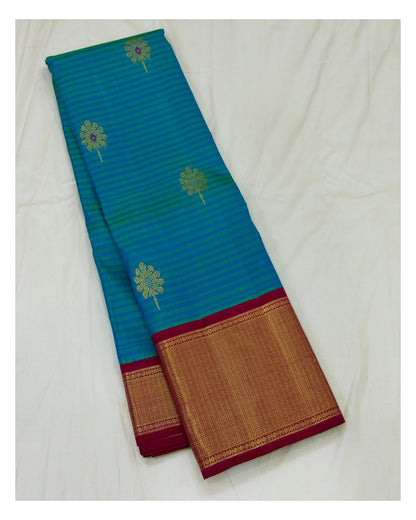 Full view of teal blue saree with gold-toned motifs and magenta woven border