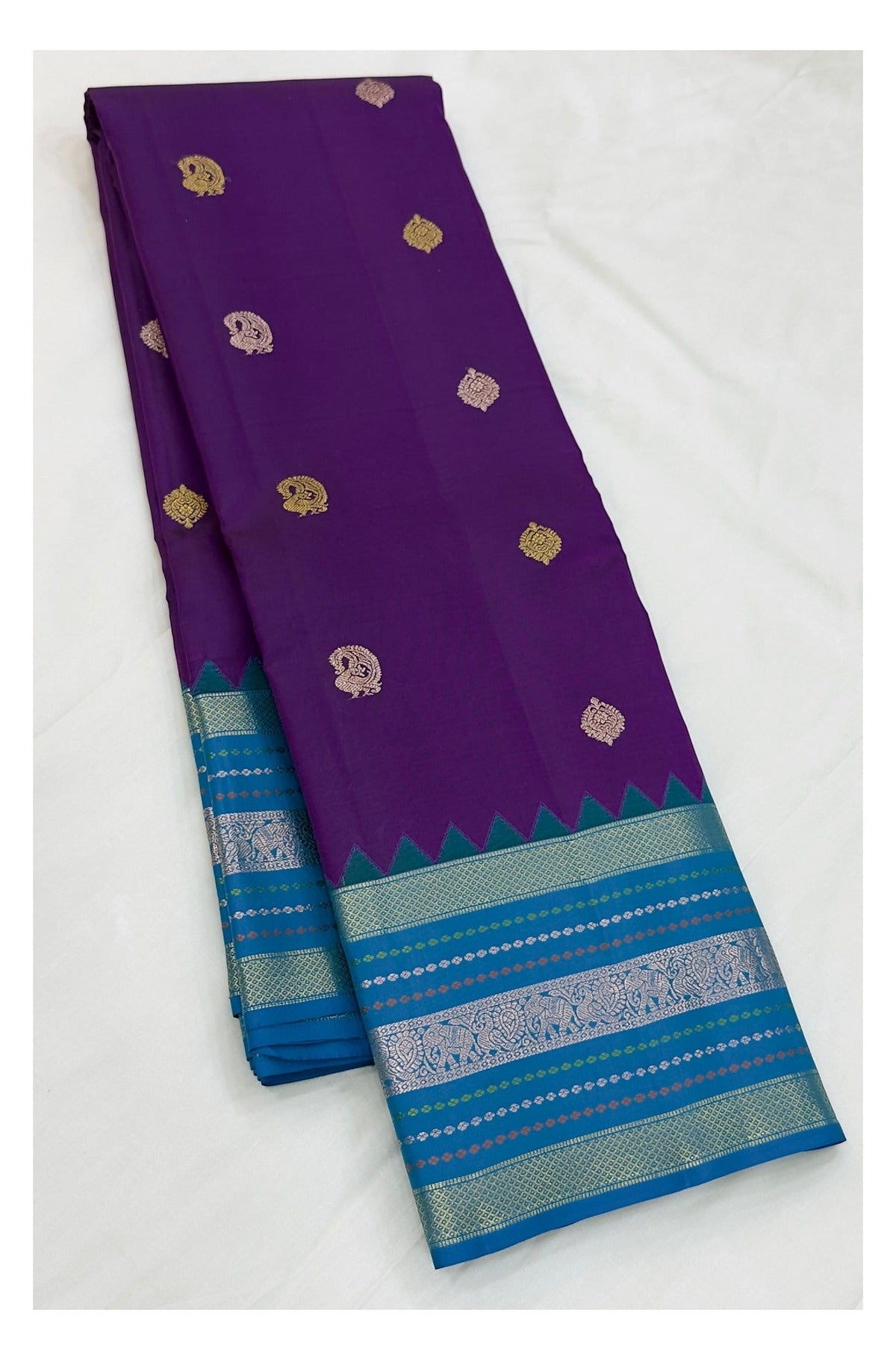Purple Kanchipuram silk saree with gold-toned buttas and teal blue contrast border