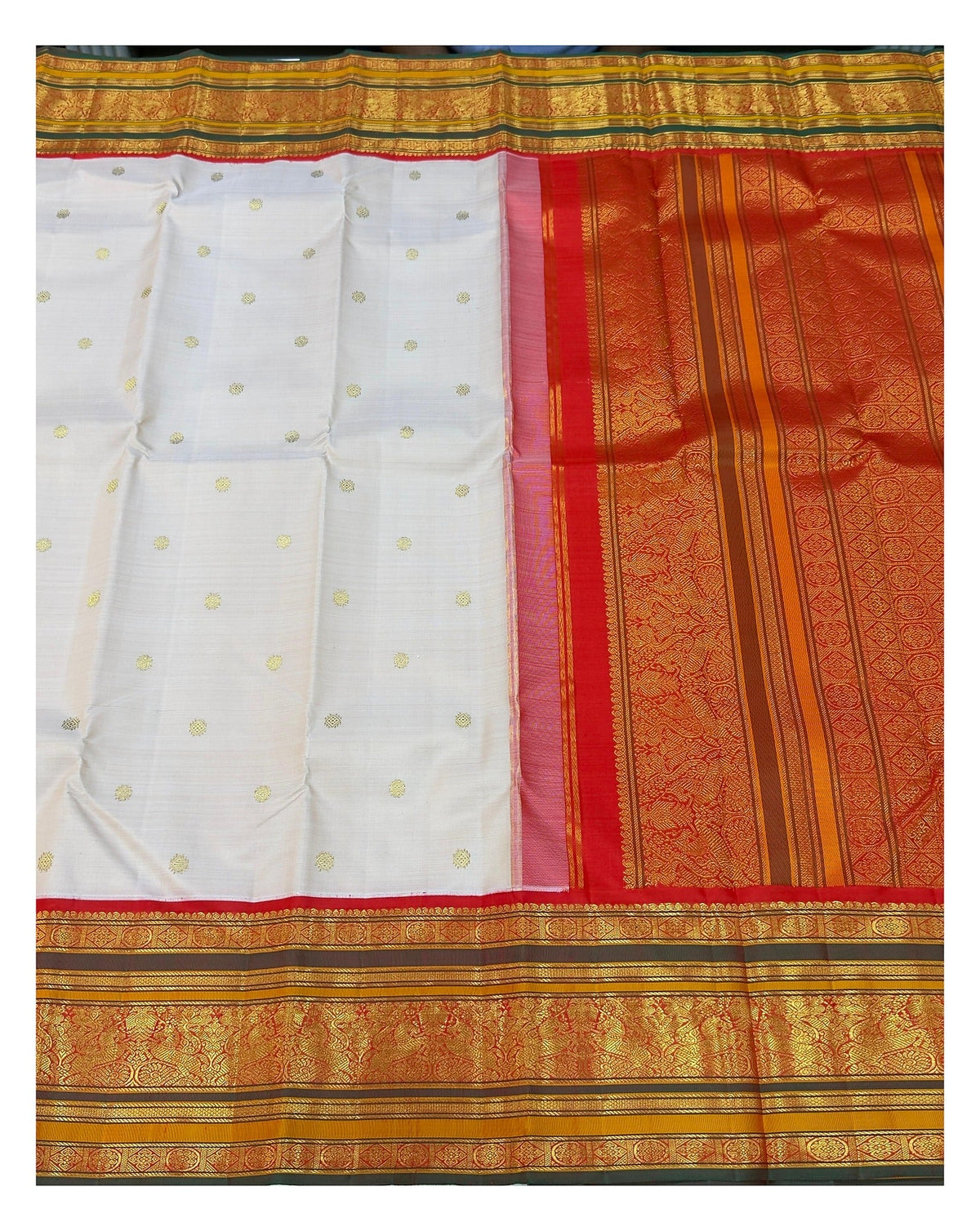 Open view of the saree showing blush pink body with gold-toned buttas and richly woven red pallu