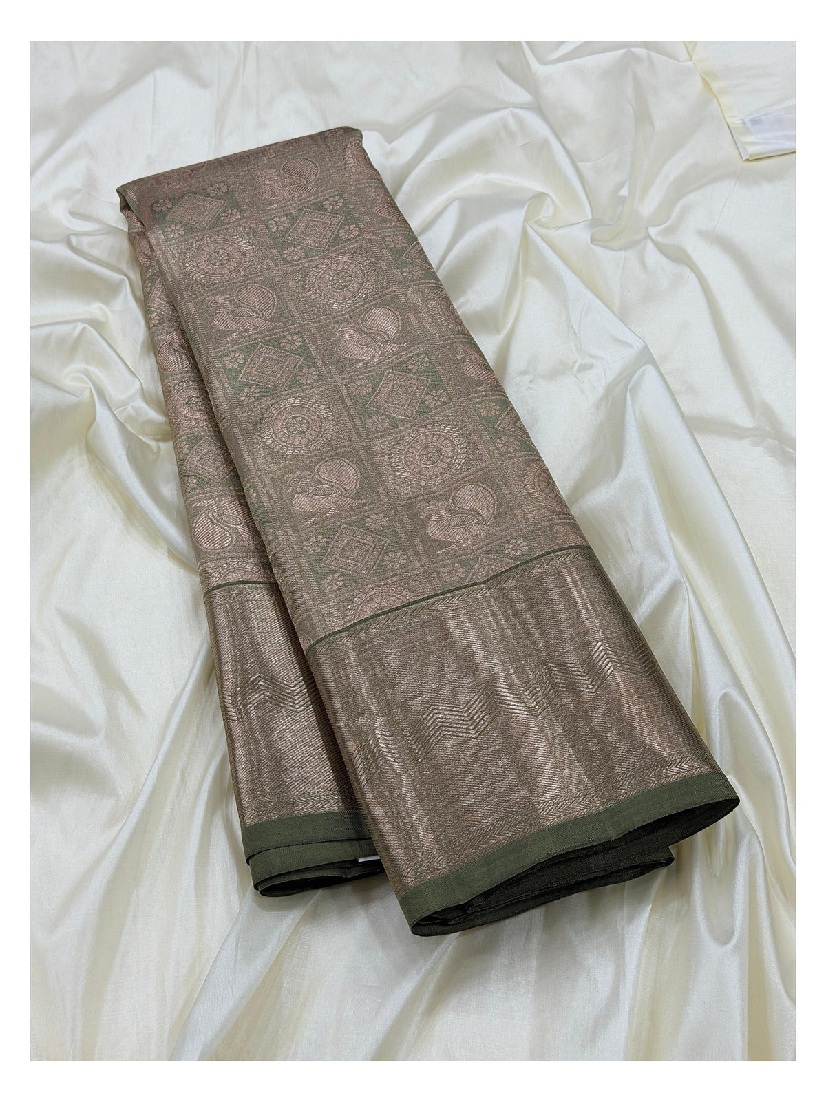 Folded sage green Kanchipuram silk saree with antique gold woven body and broad zari border