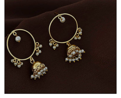 Close view of gold polish circle jhumka earrings with pearl bead detail