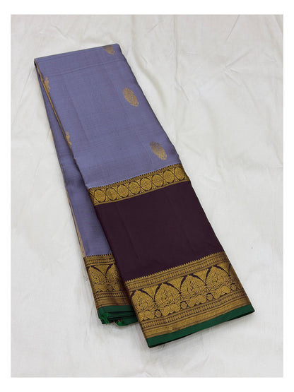 Folded lavender saree showing gold woven body motifs, deep plum border, and green edge