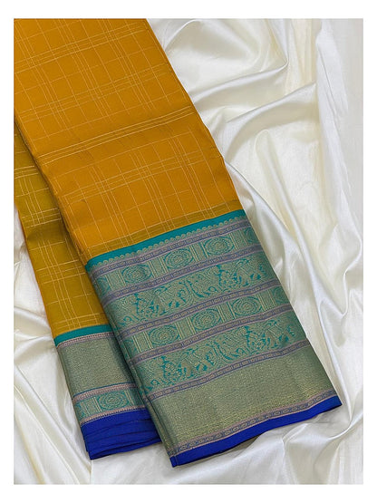 Folded mustard saree showing fine check lines and a detailed teal woven border