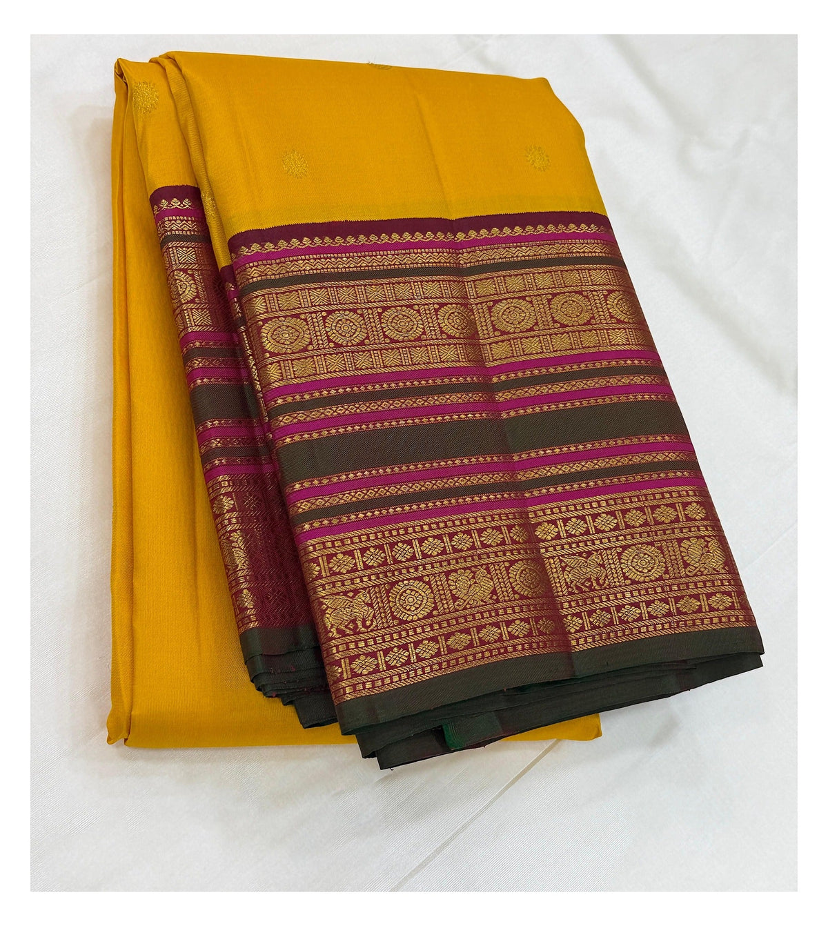 Mustard yellow handwoven Kanchipuram silk saree folded to show broad magenta and gold-toned border