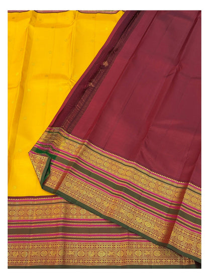 Contrast maroon blouse piece and border detail of the mustard yellow handwoven Kanchipuram silk saree