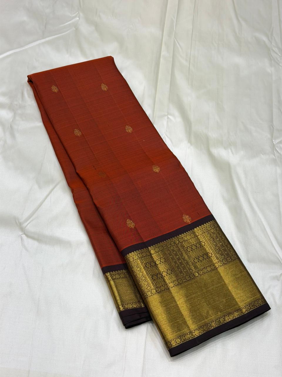 Traditional rust-orange saree with rich maroon pallu and gold detailing
