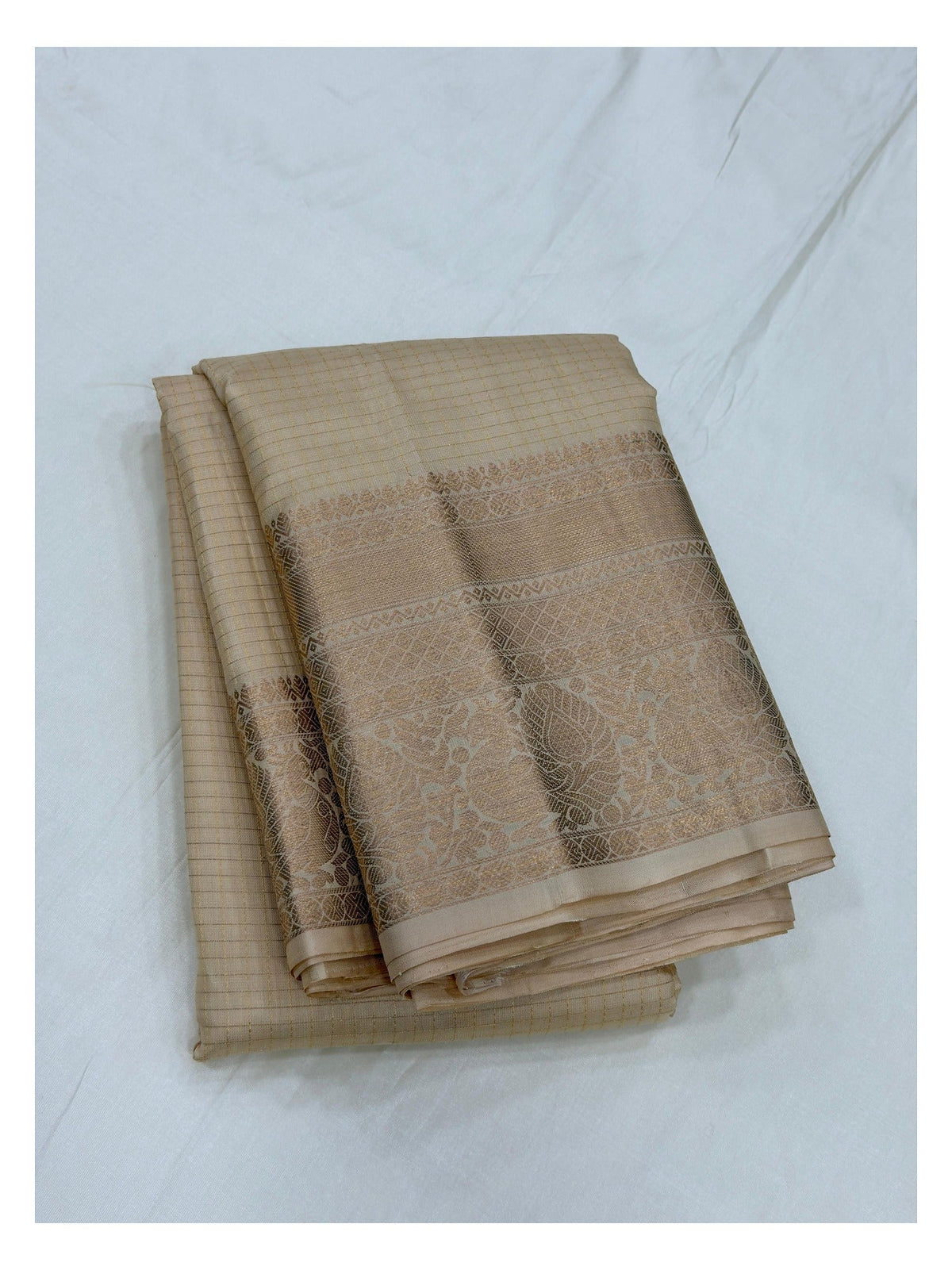 Pure silk saree in soft gold beige folded to highlight the zari border