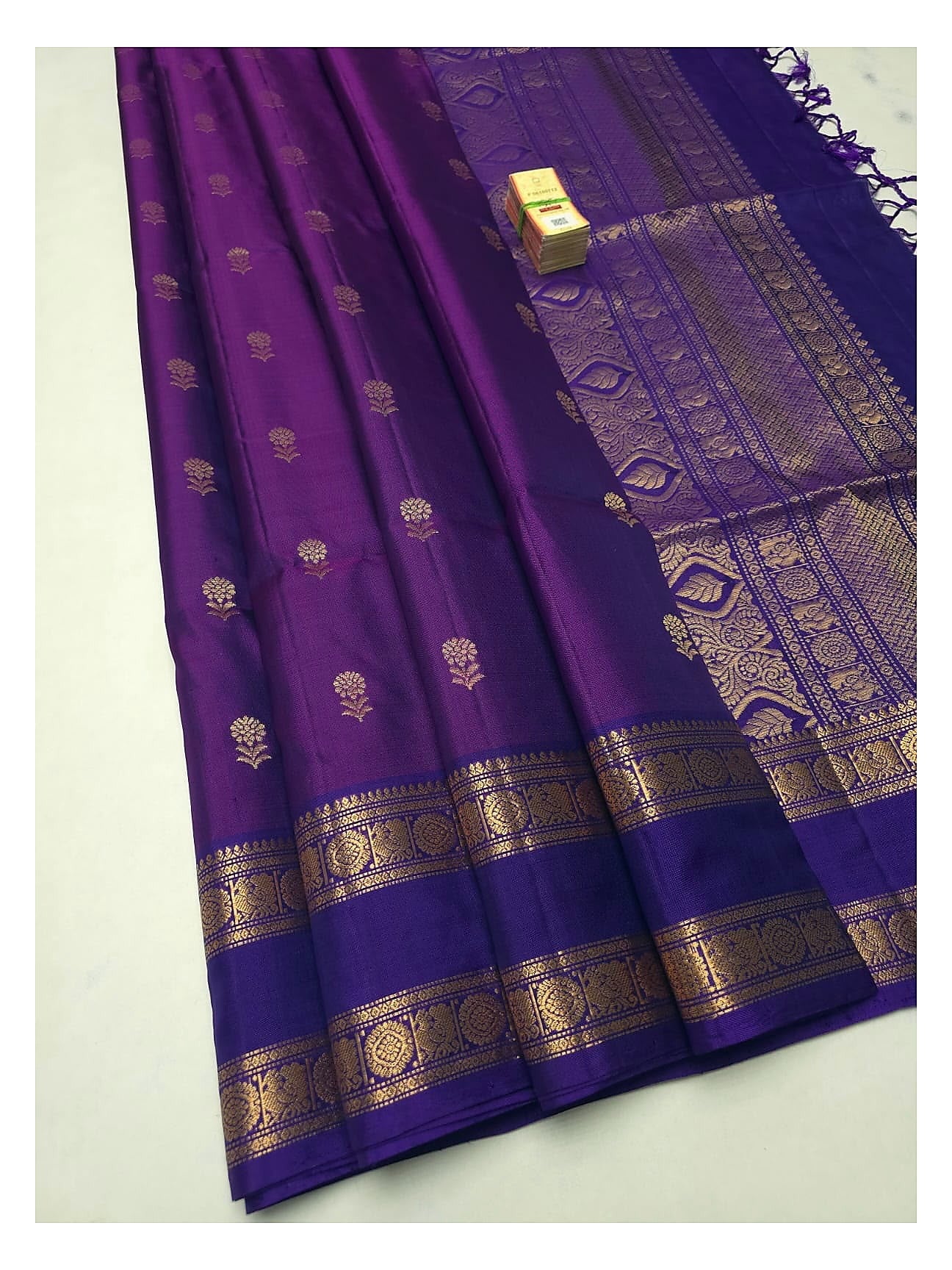 Royal purple soft silk saree with gold-toned floral buttas, traditional woven border and rich pallu